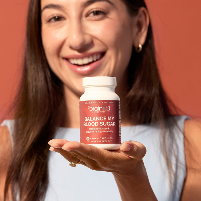 BrainMD Balance My Blood Sugar: smiling woman holding a supplement bottle, orange background