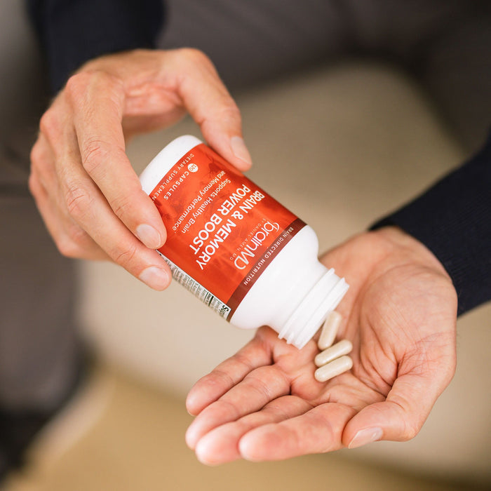 BrainMD Brain & Memory Power Boost: man pours white capsules from a red supplement bottle into his hand