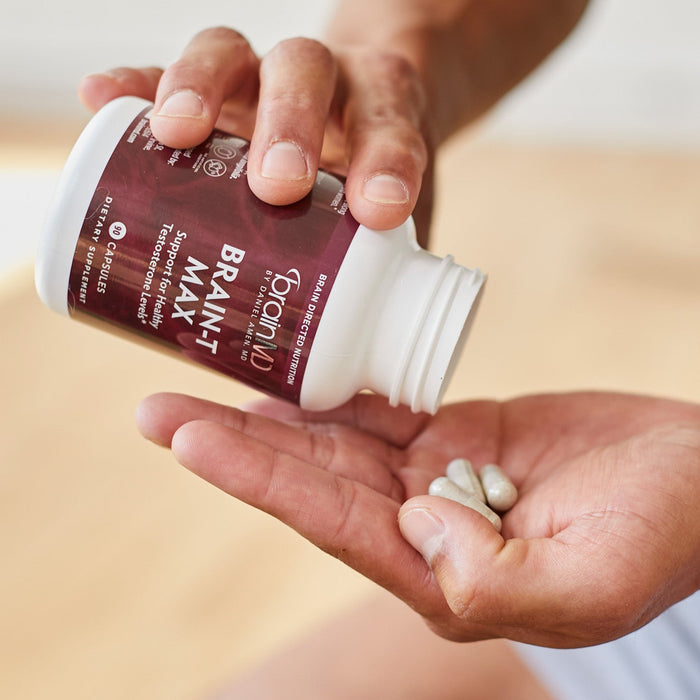 BrainMD Brain-T MAX: man pouring capsules from a brown supplement bottle into his hand