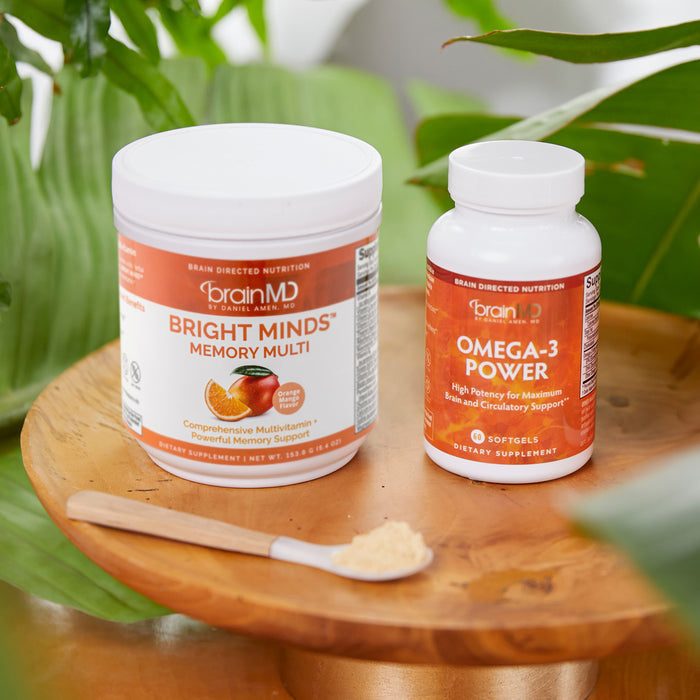 BrainMD BRIGHT MINDS Memory Bundle: two orange bottles and an orange and white container on small table surrounded by plants