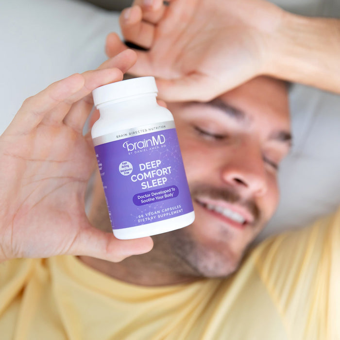 BrainMD Deep Comfort Sleep: blurred image of a man in the background holding a purple supplement bottle toward the camera