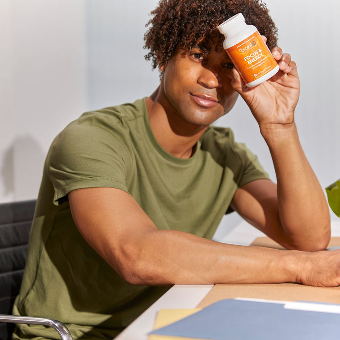 BrainMD Focus & Energy: man in an office holding an orange supplement bottle against his forehead