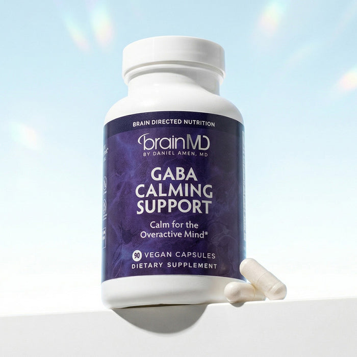 Purple supplement bottle with white capsules at the base against a light blue background.