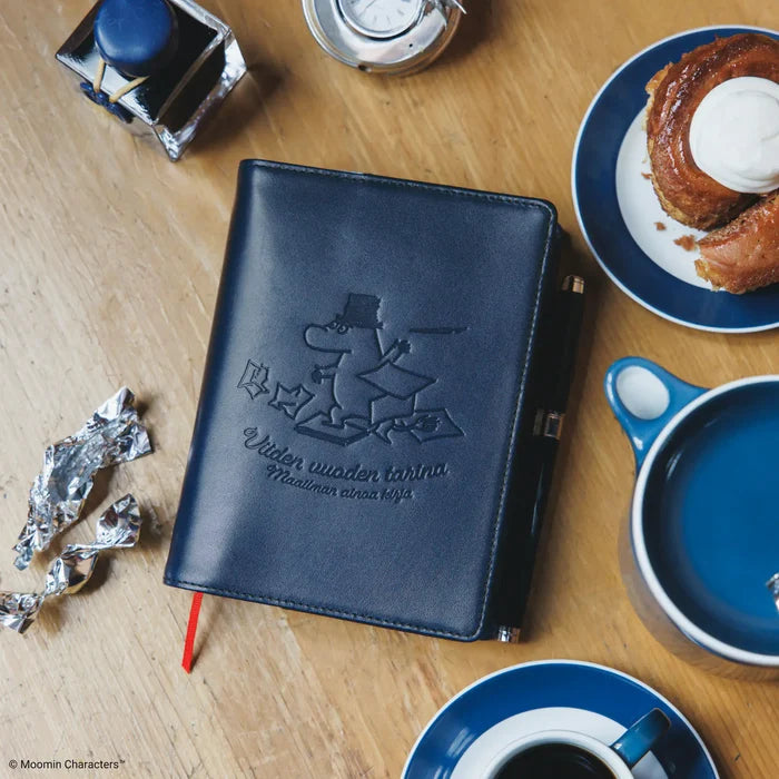 The closed cover on a wooden table with coffee and pastries alongside