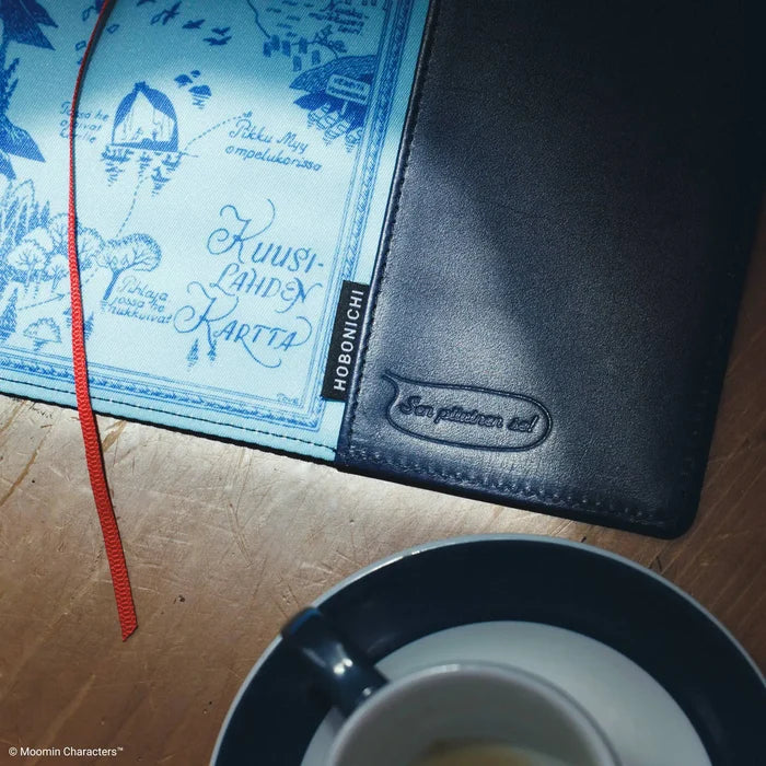 A close-up of the cover open on a table, the blue lining showing beside a cup