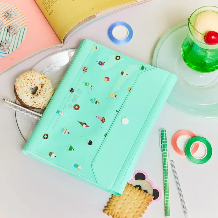 The closed cover on a table with a biscuit, rolls of tape and a green cream soda