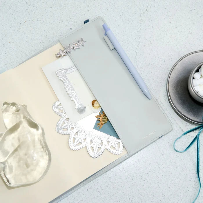The cover open on a pale surface among lace, a glass ornament and a clock
