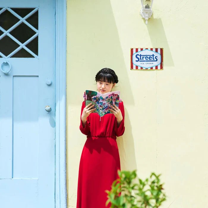 A woman holding the cover open in front of a pale blue door