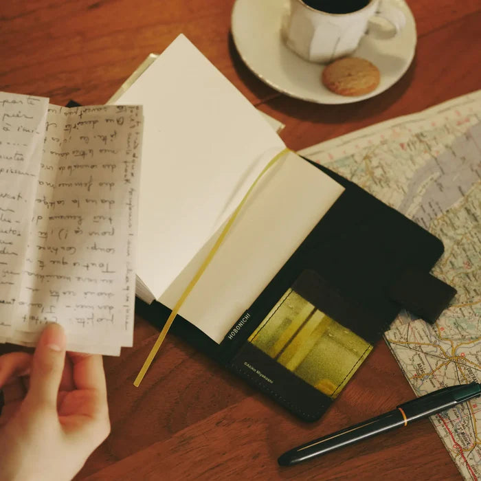 Hands writing in the open techo on a map-covered desk