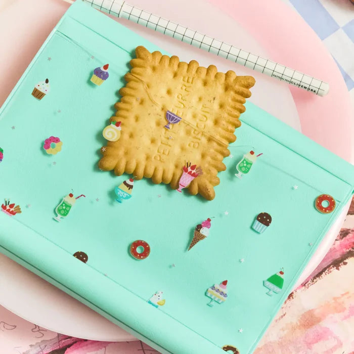 A close-up with a biscuit resting on the cover, the sweets print all around