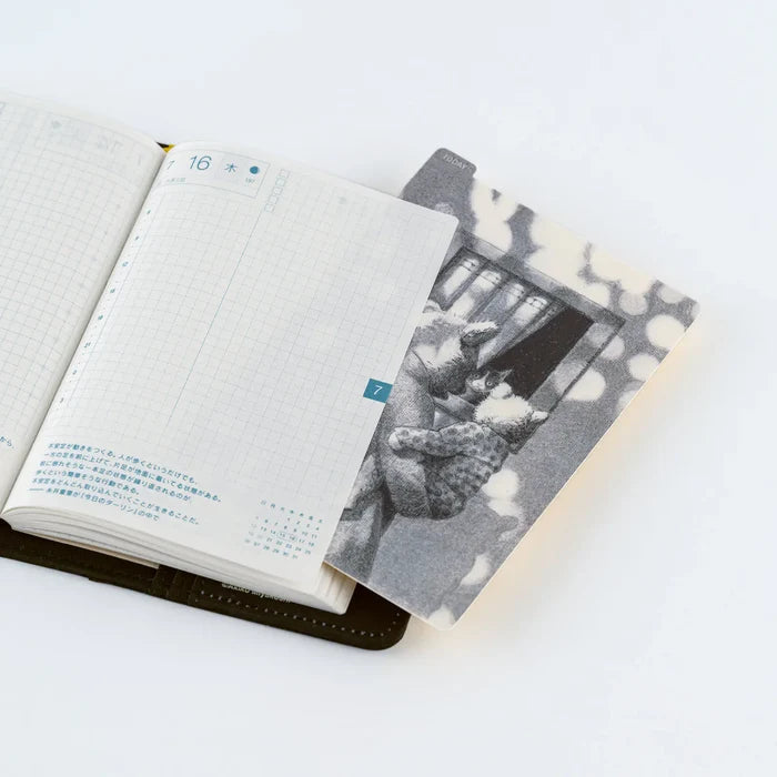 A pencil board from the series slipped into an open techo, sitting flat beneath the page