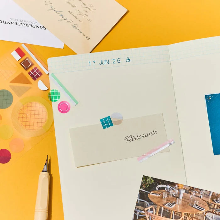 A journal page laid out with an envelope, tape, a pen and strips of photographs