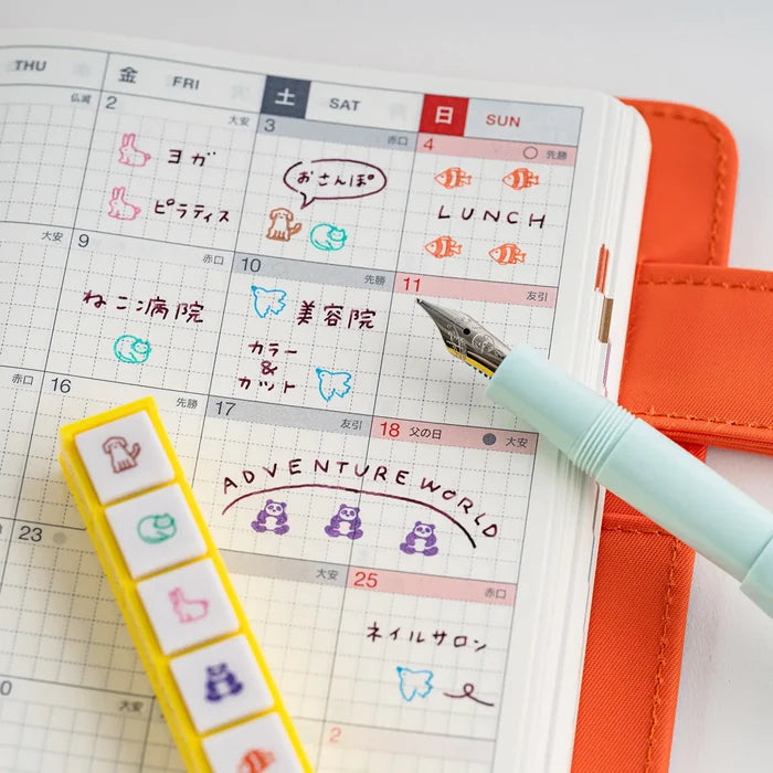 A techo page stamped with icons, a fountain pen and highlighters laid beside it