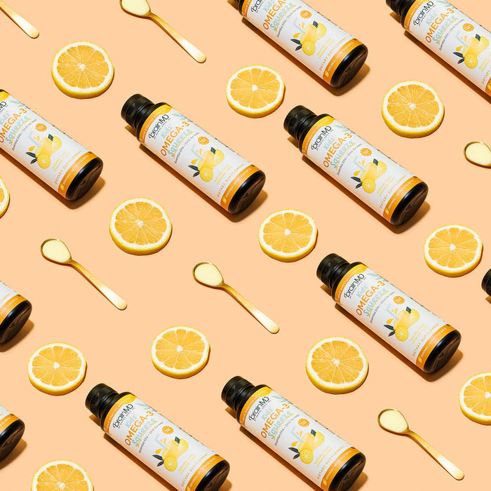 BrainMD Kids' Omega-3 Squeeze: pattern of orange & white supplement bottles, spoons and orange slices on a peach-hued surface