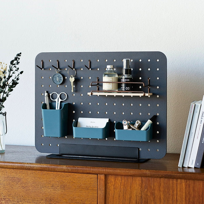 Teal PEGGY mini containers displayed on a pegboard as part of a desk organisation setup.