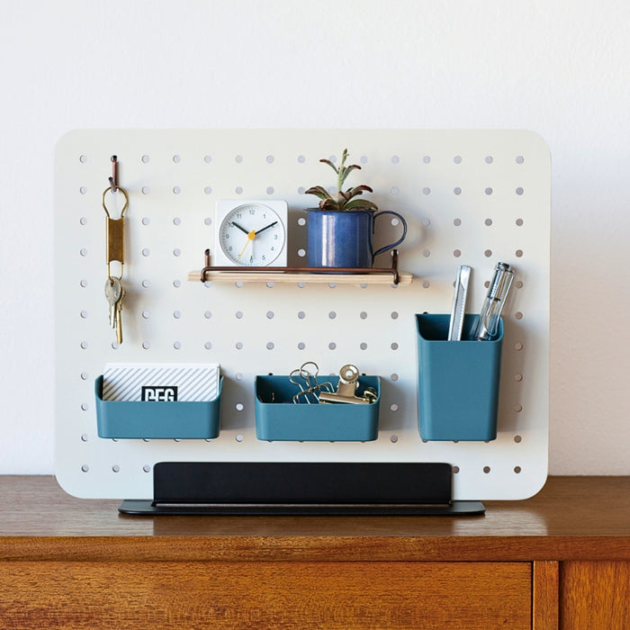 PEGGY Accessories pen stand displayed on a pegboard above a desk with stationery and storage items.