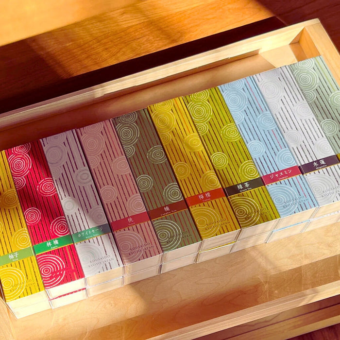 Assorted Kousaido Hyakurakukou Japanese incense boxes displayed in a wooden drawer.