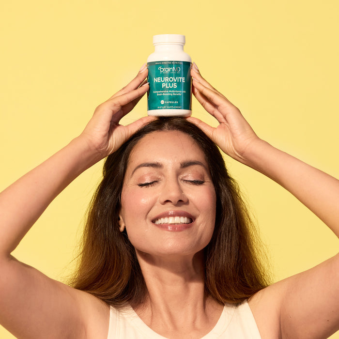 BrainMD Memory Bundle: woman balancing a green supplement bottle on her head, yellow background