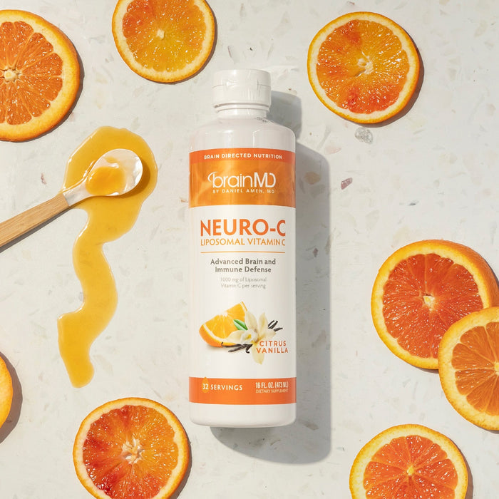 BrainMD Neuro-C Vitamin C: orange and white supplement bottle surrounded by orange slices against an off-white background