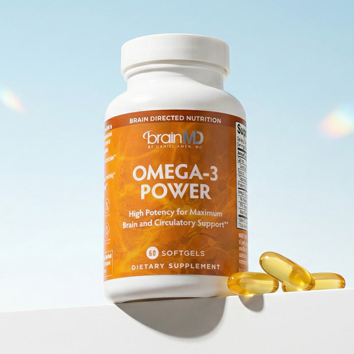 Orange supplement bottle with golden gelcaps at the base against a powder blue background.
