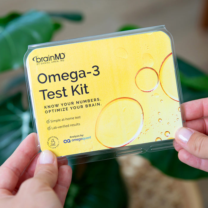 Hands holding the BrainMD Omega-3 Test Kit, a simple at-home omega-3 blood test with lab-verified results