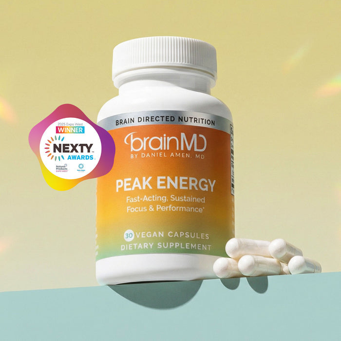 Orange supplement bottle with white capsules against a light yellow background.