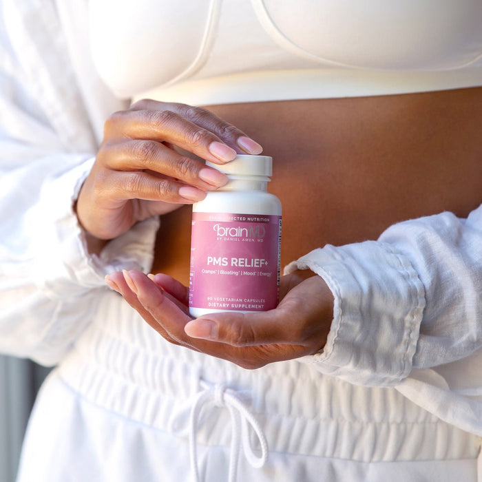 BrainMD PMS Relief+: woman holding a pink supplement bottle