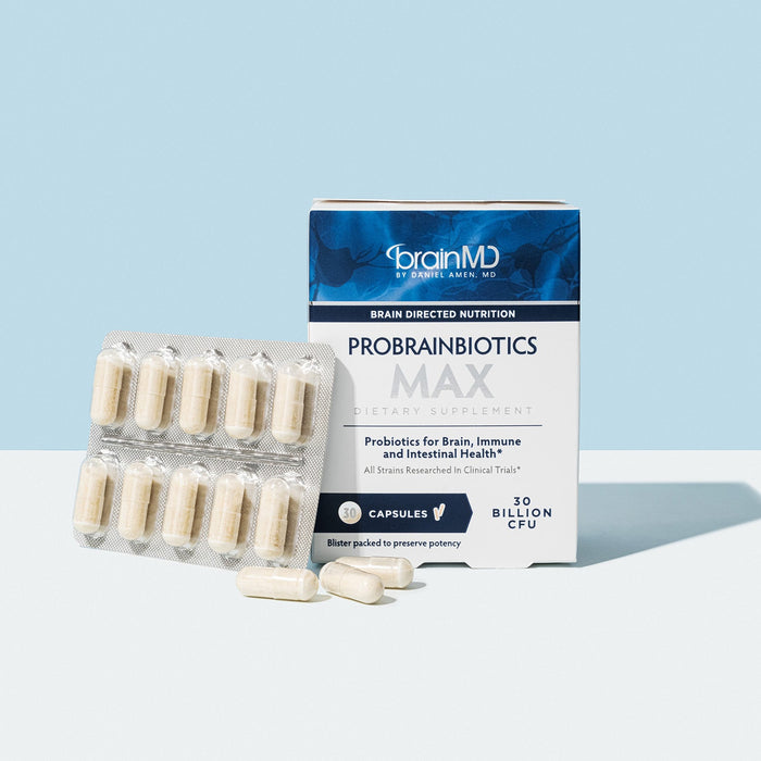 BrainMD ProBrainBiotics MAX: blue & white supplement box with loose and packaged capsules against a light blue background