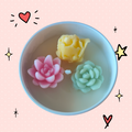 Succulent Candles in Tin Tray bobbing in water.