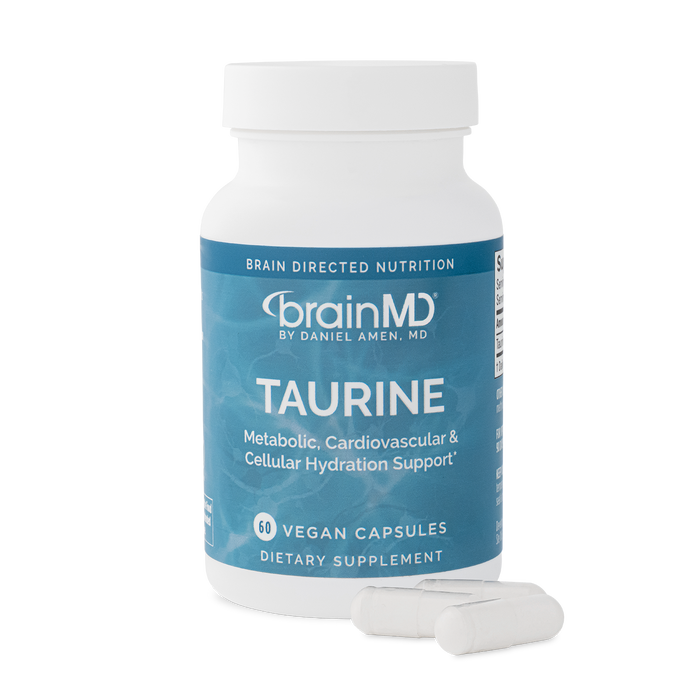 Supplement bottle labeled 'Taurine' by BrainMD with capsules laying in front of it.