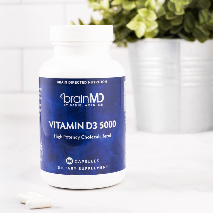 BrainMD Vitamin D3 5000: a purple supplement bottle and white capsules against an interior white background